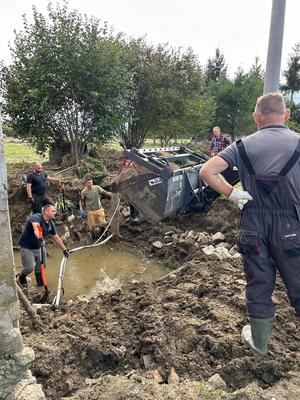 Zdjęcie przedstawiające prace przy zasypywaniu dołu.