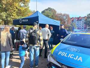 Zdjęcie przedstawiające policjanta, radiowóz i uczestników.