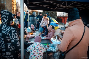 Zdjęcie przedstawiające stoisko profilaktyczne oraz dzieci kolorujące kolorowanki.