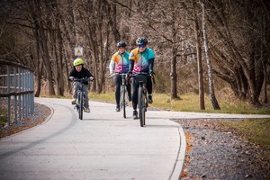 Zdjęcie przedstawiając trzy osoby jadące na rowerze.
