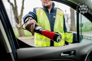 Zdjęcie Policjanta trzymającego urządzenie do badania stanu trzeźwości.