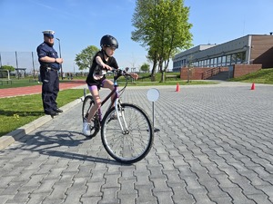 Zdjęcie przedstawiające Policjanta i dziecko na rowerze.