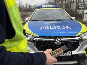 Zdjęcie przedstawiające Policjanta trzymającego urządzenie do badania stanu trzeźwości.