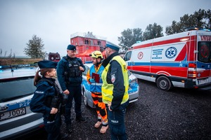 Zdjęcie przedstawiające policjantów, strażaka, radiowozów strażackich oraz karetki.
