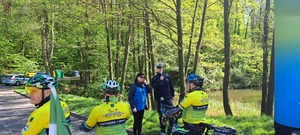 Zdjęcie przedstawiające osoby na rowerach oraz Policjant.
