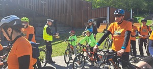 Zdjęcie przedstawiające osoby na rowerach oraz Policjant.
