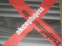 Zdjęcie plakatu, gdzie osoba zagląda przez okno zza zasłoniętych żaluzji.