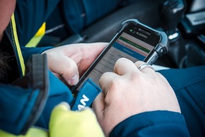 Zdjęcie Policjanta w trakcie sprawdzania na urządzeniu danych osobowych kierowcy.