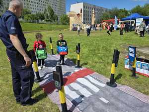 Zdjęcie przedstawiające Policjanta oraz dzieci ubrane w pluszowe pojazdy.
