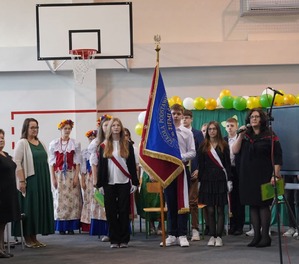 Zdjęcie przedstawiające uczniów niosących poczet sztandarowy.