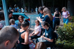 Zdjęcie przedstawiające dziewczyny z klas mundurowych w trakcie malowania twarzy dziecka i robienia warkoczyków.