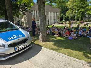 Zdjęcie przedstawiające dzieci oraz radiowóz i Policjantkę.