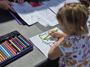 Zdjęcie dzieci, które rysują kolorowankę przy stoisku profilaktycznym.