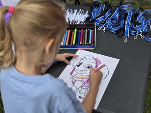 Zdjęcie dzieci, które rysują kolorowankę przy stoisku profilaktycznym.