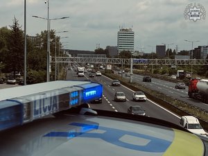 Zdjęcie przedstawiające radiowóz oraz samochody jadące drogą.
