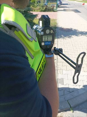 Zdjęcie przedstawiające policjanta ruchu drogowego trzymającego radar.