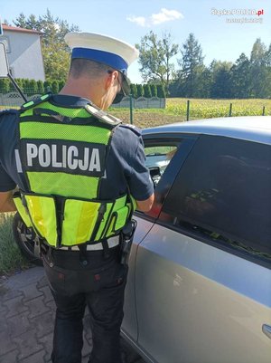 Zdjęcie przedstawiające policjanta ruchu drogowego oraz samochód osobowy.