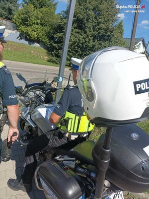 Zdjęcie przedstawiające policjantów ruchu drogowego oraz motocykl.