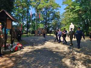 Zdjęcie zebranych na uroczystościach i składających kwiaty.