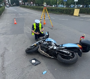 Zdjęcie policjanta i uszkodzonego motocykla.