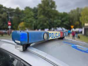 Zdjęcie przedstawiające radiowóz oraz osoby protestujące.