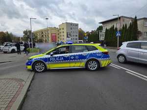 Zdjęcie przedstawiające radiowóz oraz osoby protestujące.