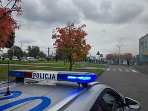 Zdjęcie przedstawiające radiowóz oraz osoby protestujące.