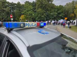 Zdjęcie przedstawiające radiowóz oraz osoby protestujące.