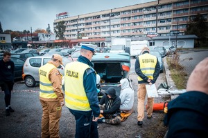 Zdjęcie przedstawiające uczestników biorących udział w wykonywanym zadaniu oraz policjanta.