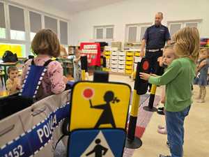 Zdjęcie przedstawiające bawiące się dzieci miasteczkiem ruchu drogowego.