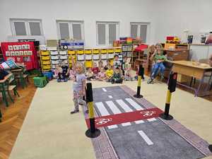 Zdjęcie przedstawiające bawiące się dzieci miasteczkiem ruchu drogowego.