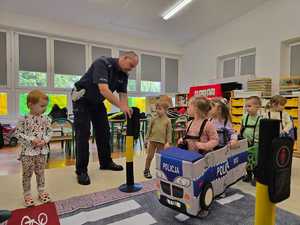 Zdjęcie przedstawiające bawiące się dzieci miasteczkiem ruchu drogowego.