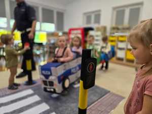 Zdjęcie przedstawiające bawiące się dzieci miasteczkiem ruchu drogowego.