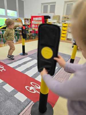 Zdjęcie przedstawiające bawiące się dzieci miasteczkiem ruchu drogowego.