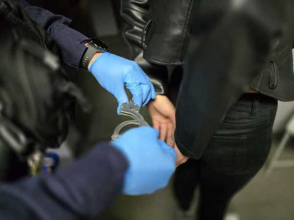 Zdjęcie kobiety w trakcie zakładania jej kajdanek.