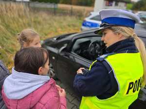 Zdjęcie policjantkę oraz dzieci w trakcie kontroli drogowej.