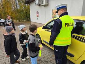 Zdjęcie policjanta oraz dzieci w trakcie kontroli drogowej.