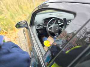 Zdjęcie policjanta w trakcie kontroli drogowej.