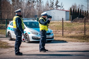 Zdjęcie przedstawiające policjantów ruchu drogowego, w trakcie pracy na urządzeniu do mierzenia prędkości.