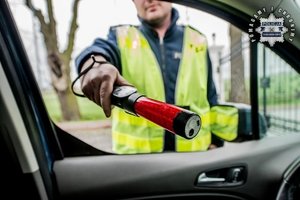 Zdjęcie policjanta trzymającego urządzenie do badania stanu trzeźwości.