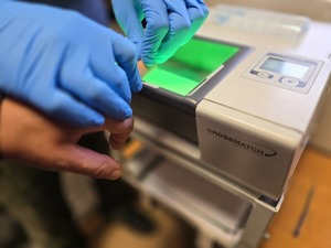 Zdjęcie mężczyzny, które policjant pobiera odciski linii papilarnych.