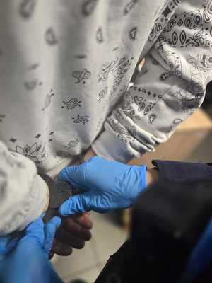 Zdjęcie zatrzymanego oraz policjanta zakładającego mu kajdanki.