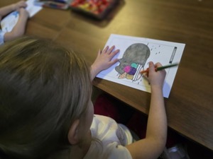 Zdjęcie przedstawiające dziewczynkę kolorującą przy policyjnym stoisku.