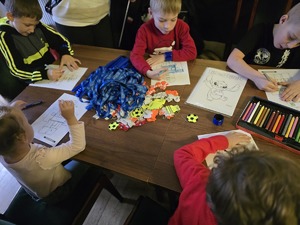 Zdjęcie przedstawiające dzieci, kolorujące przy policyjnym stoisku.