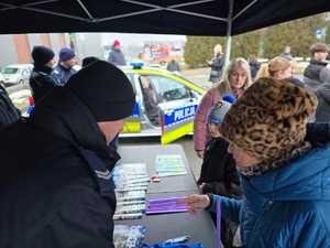 Zdjęcie przedstawiające Policjantów oraz zebranych przy stoisku profilaktycznym.