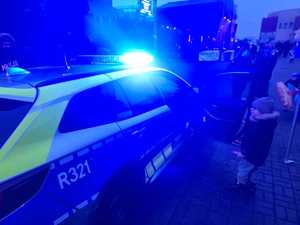 Zdjęcie przedstawiające dziecko stojące przy radiowozie.