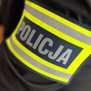 Napis Policja na opasce umieszczonej na rękawie kurtki.