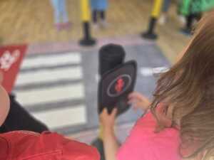 Dzieci bawiące się miasteczkiem ruchu drogowego.