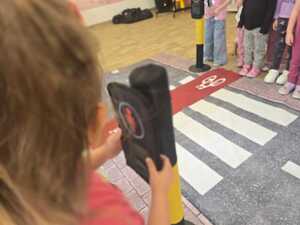 Dzieci bawiące się miasteczkiem ruchu drogowego.