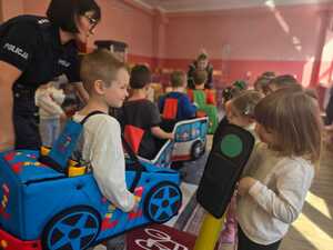 Dzieci bawiące się miasteczkiem ruchu drogowego.